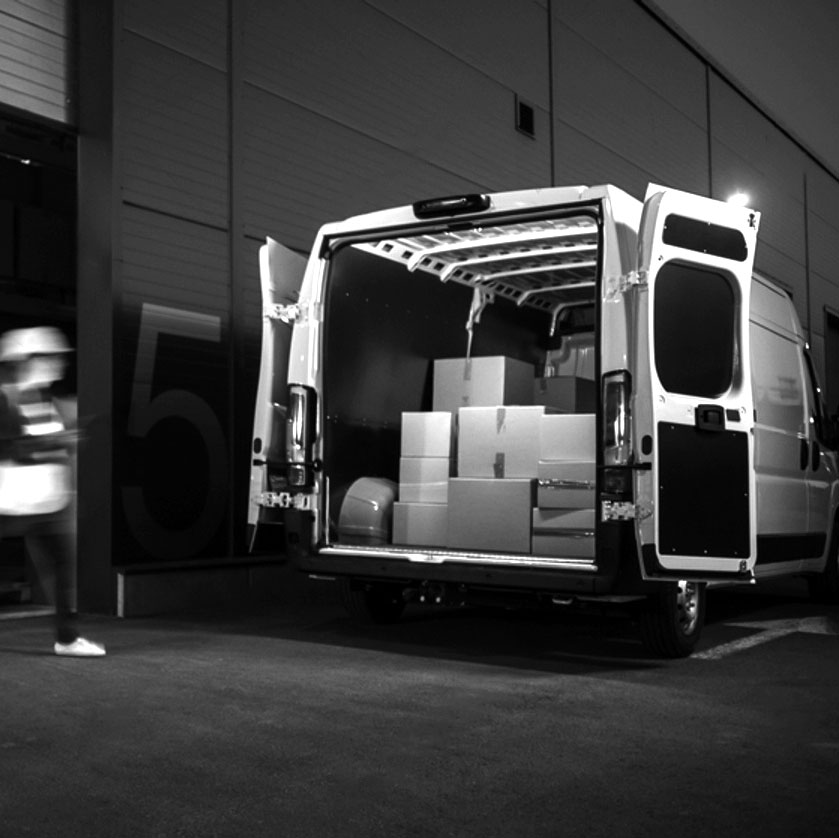 Furgoneta con las puertas traseras abiertas y cajas cargadas